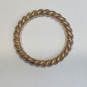 May include: A twisted gold ring with a copper finish.