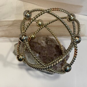 May include: A silver and copper toned bracelet with multiple strands of twisted wire and round beads.