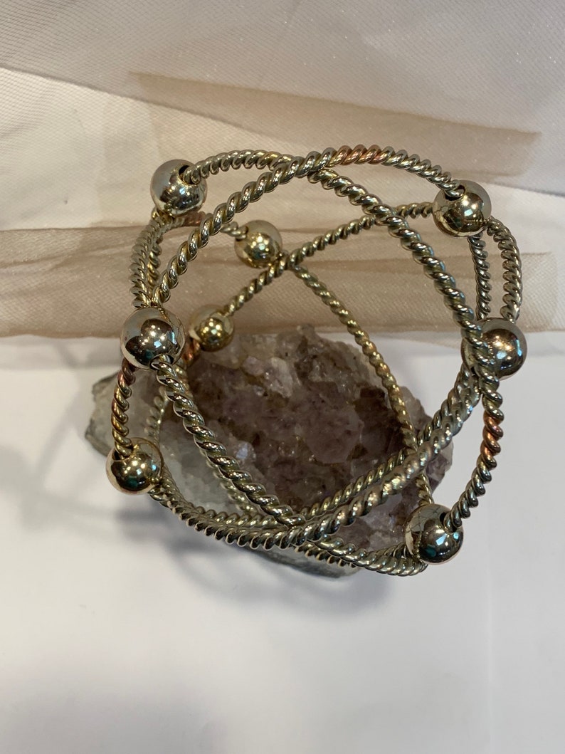 May include: A silver and copper toned bracelet with multiple strands of twisted wire and round beads.