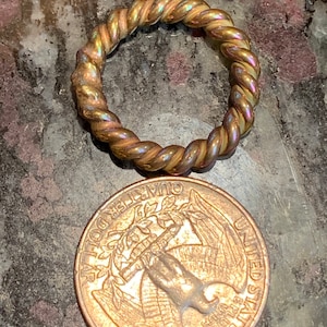 May include: A gold-toned twisted wire ring, approximately the size of a US quarter.
