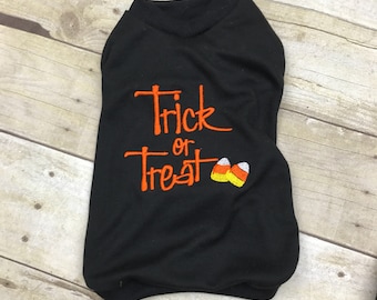 May include: Black dog shirt with orange embroidery that says "Trick or Treat" and two candy corn designs.