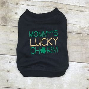 May include: Black t-shirt with the text "Mommy's Lucky Charm" in green and gold lettering with a green shamrock.