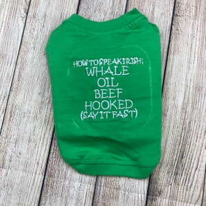 May include: Green t-shirt with white text that reads "How to speak Irish! Whale Oil Beef Hooked (Say it fast)"