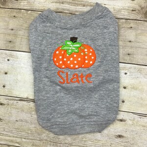 Peut inclure: T-shirt gris pour chien avec une citrouille orange &agrave; pois blancs et une tige verte. Le t-shirt est personnalis&eacute; avec le nom "Slate".