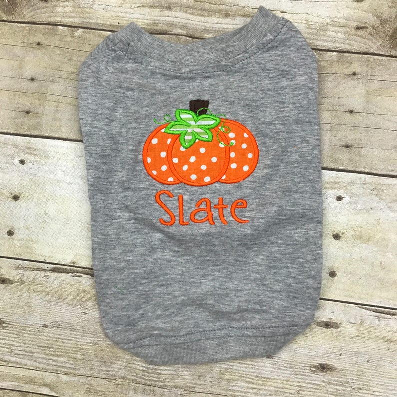 Peut inclure: T-shirt gris pour chien avec une citrouille orange &agrave; pois blancs et une tige verte. Le t-shirt est personnalis&eacute; avec le nom "Slate".