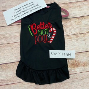 May include: Black dog shirt with a white ruffle hem. The shirt has red and green embroidery that says "Better Not Pout" with a candy cane and snowflake. The shirt is size X Large.