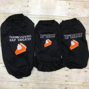 May include: Three black Thanksgiving dog sweaters with a pumpkin pie graphic and the text "Thanksgiving Nap Sweater".