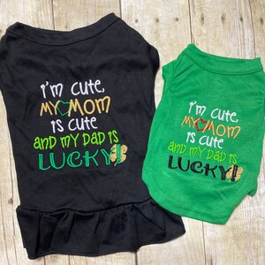 May include: Two black and green dog shirts with the text "I'm cute, MY MOM is cute and my Dad is LUCKY" on them. The shirts are embroidered with a heart and a shamrock.