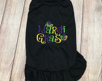 May include: Black dog shirt with a purple and green embroidered design that says "Mardi Gras" with a jester's hat and fleur-de-lis.