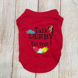 May include: Red dog shirt with the text "Talk Derby to me!" embroidered on the back. The shirt features a small horse and flower embroidery.