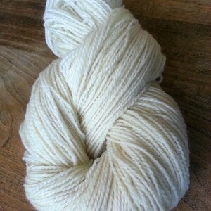 May include: A skein of off-white yarn, wound into a loose ball shape.