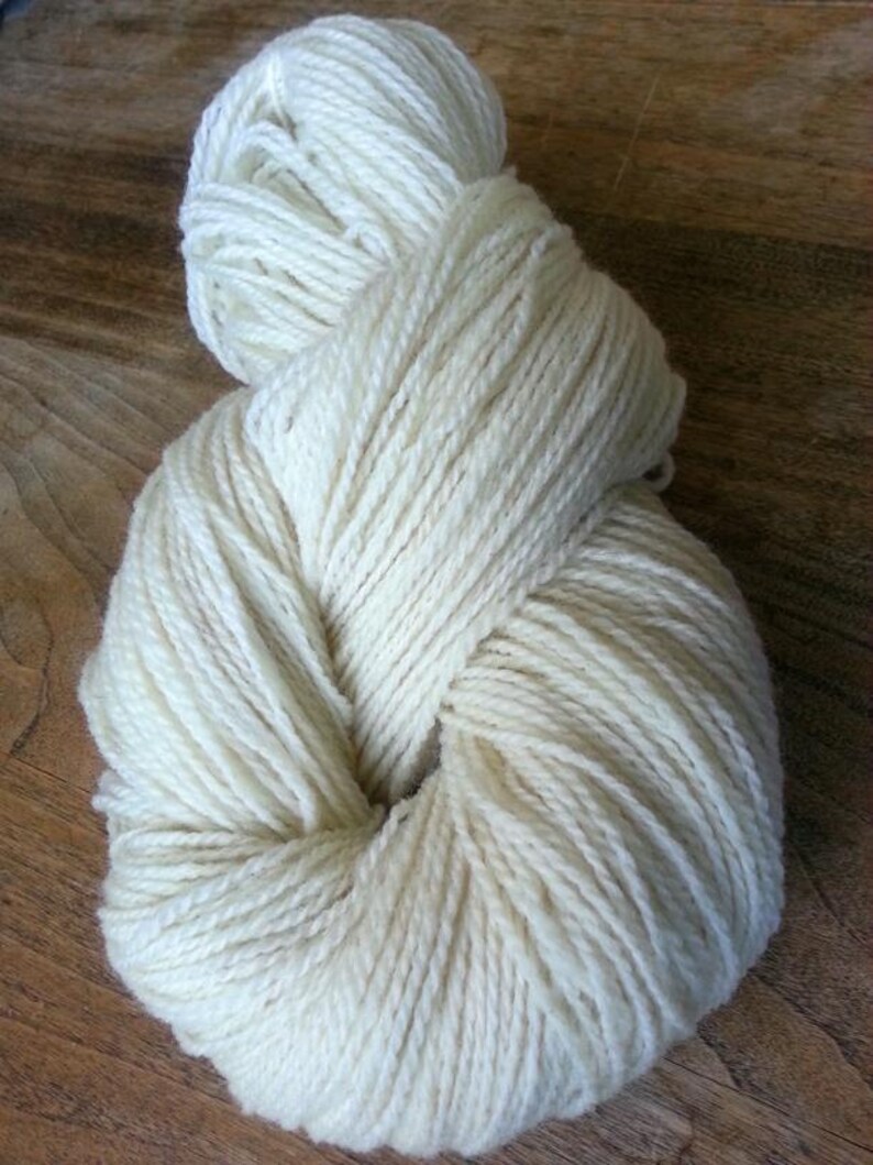 May include: A skein of off-white yarn, wound into a loose ball shape.