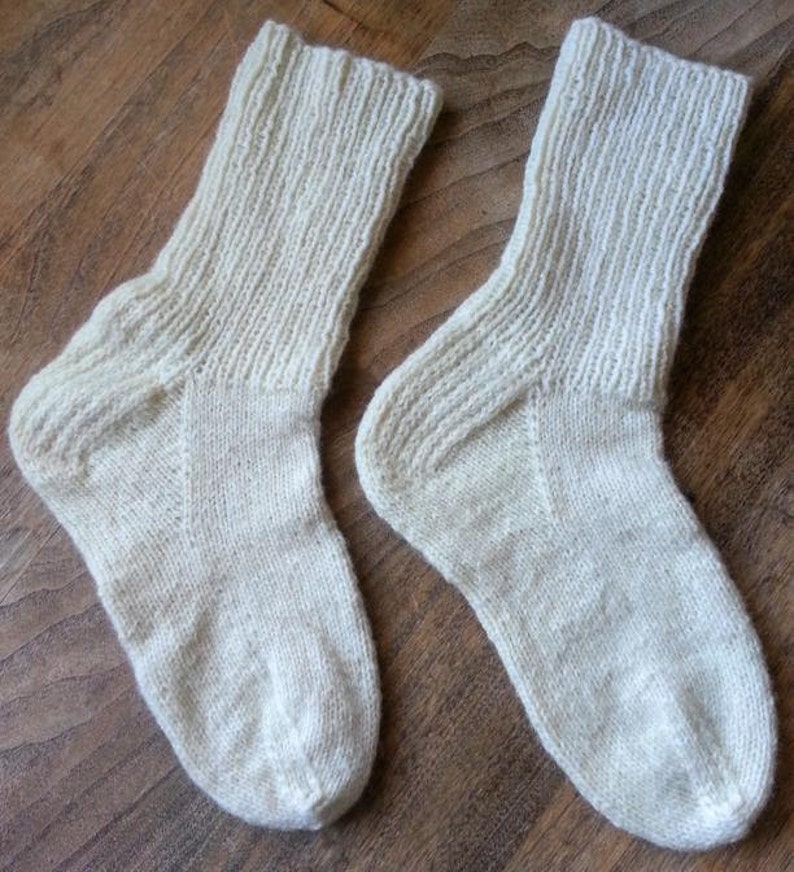 May include: Two pairs of white knitted socks. The socks are made of a soft, natural fiber and have a ribbed texture.