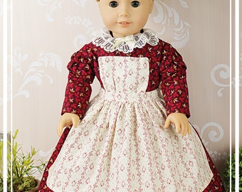 1860s-style day dress, pinner apron, and cap designed for 18-inch dolls.