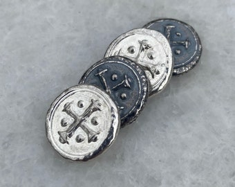 May include: Four silver-toned metal buttons with a cross design and a raised edge. The buttons are arranged in a row, with the largest button at the bottom and the smallest button at the top.