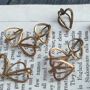 May include: A collection of gold-toned metal leaf-shaped charms. The charms are delicate and intricate, with a cutout design. They are perfect for adding a touch of elegance to jewelry, crafts, or home decor.