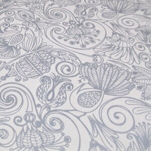 May include: A white fabric with a gray floral pattern. The pattern features stylized flowers, leaves, and birds. The design is intricate and detailed.