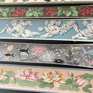May include: Four horizontal strips of wallpaper border. The top features red berries and green leaves on brown. The second shows white cherubs on light blue. The third displays fish, coral, and sea plants on gray. The bottom shows pink lotus flowers.