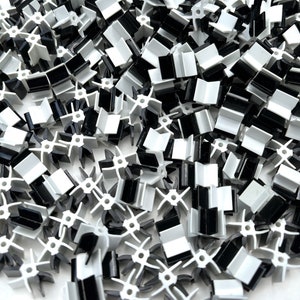 May include: A pile of black and white plastic connectors. The connectors have a star-shaped design and are used to connect pieces of plastic together.