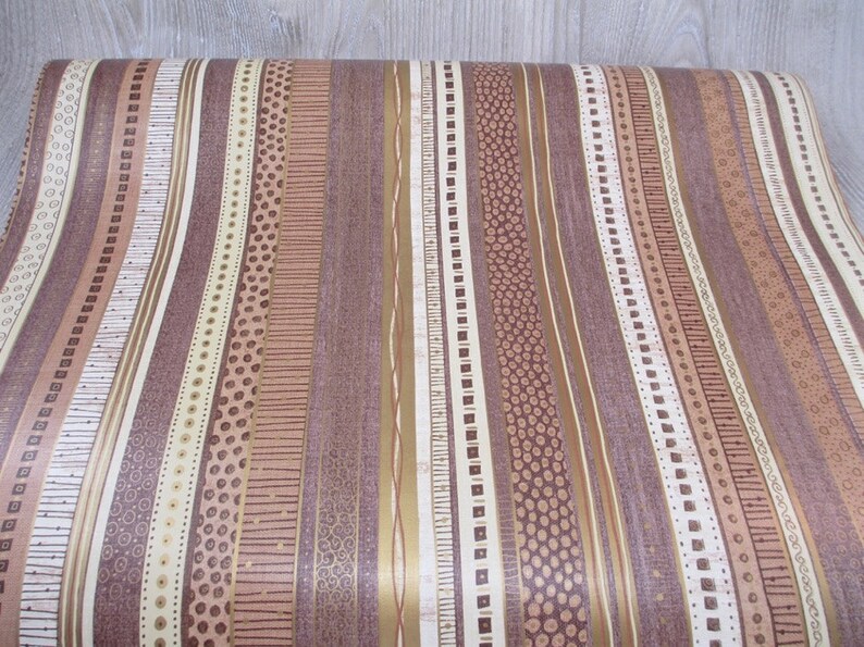 May include: A roll of brown and beige striped wallpaper with a variety of patterns, including dots, lines, and squares.