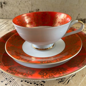 May include: A white ceramic mug with a black handle and the text "But First, Coffee" in a bold, black font. The mug is set against a blurred background, suggesting a cozy setting.