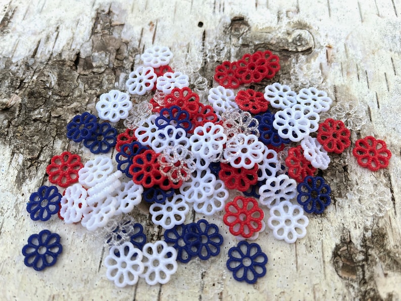 May include: A pile of red, white, and blue decorative plastic flowers. The flowers are all the same size and shape, and they are arranged in a random pattern.