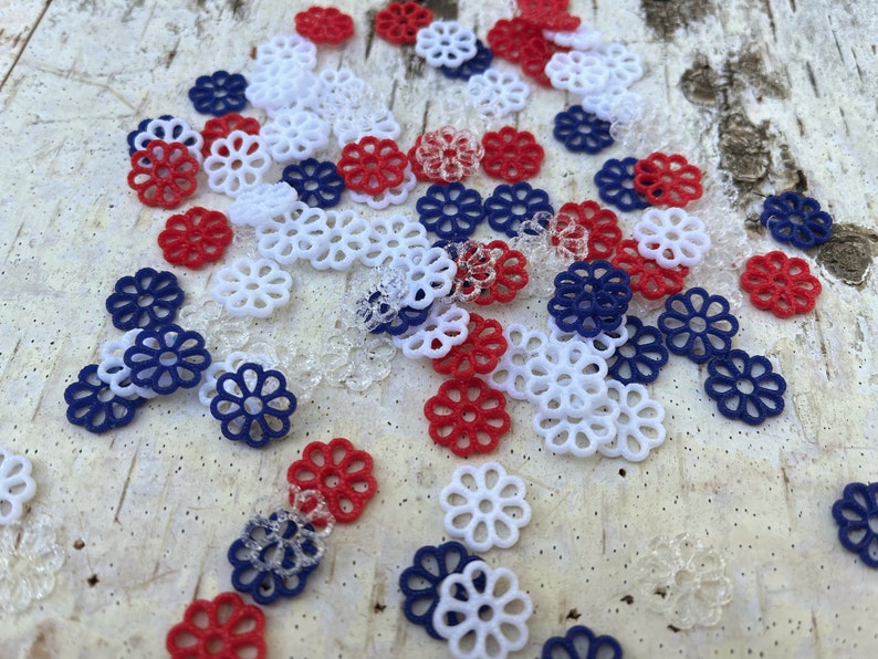 May include: Assortment of red, white, and blue decorative paper flowers. The flowers are made of a delicate, lacy material and are perfect for adding a touch of elegance to any craft project.