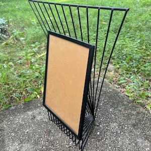 May include: A set of three ceramic mugs with a speckled, cream-colored glaze. Each mug features a different hand-painted design: a blue and green leaf, a yellow flower, and a red berry. The mugs have a simple, modern design.