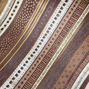 May include: A brown fabric with a repeating pattern of gold and white stripes. The stripes feature different geometric designs, including dots, squares, and swirls.