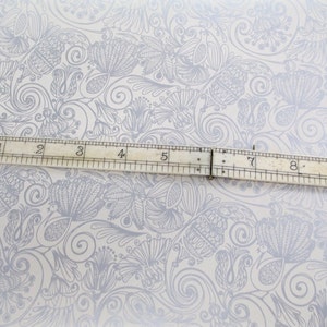 May include: A white background with a gray floral pattern. A ruler is placed horizontally across the center of the image. The ruler is marked with numbers from 1 to 10.
