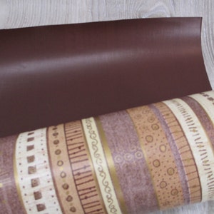 May include: A roll of brown and beige patterned wrapping paper with a solid brown sheet on top.