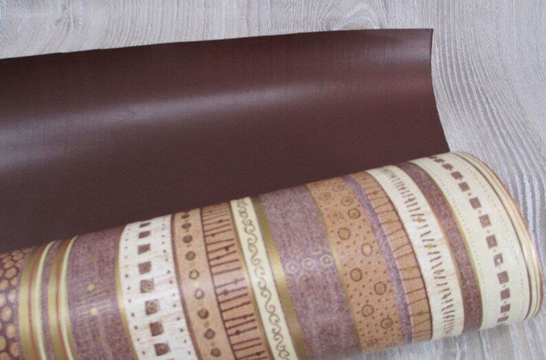 May include: A roll of brown and beige patterned wrapping paper with a solid brown sheet on top.