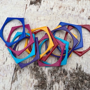 May include: A set of colorful plastic bangles in various shades of blue, yellow, purple, and red. The bangles are shaped like hexagons and are stacked on top of each other.