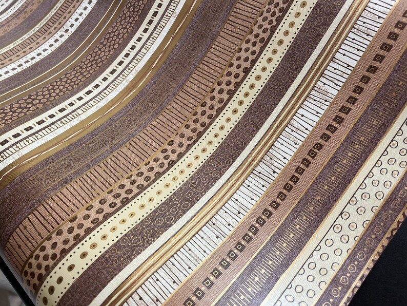 May include: A brown and beige patterned wallpaper with a repeating geometric design. The wallpaper has a subtle shimmer and a textured surface.