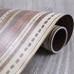 May include: A roll of brown and beige patterned contact paper with a geometric design. The paper is rolled up and the end of the roll is visible.