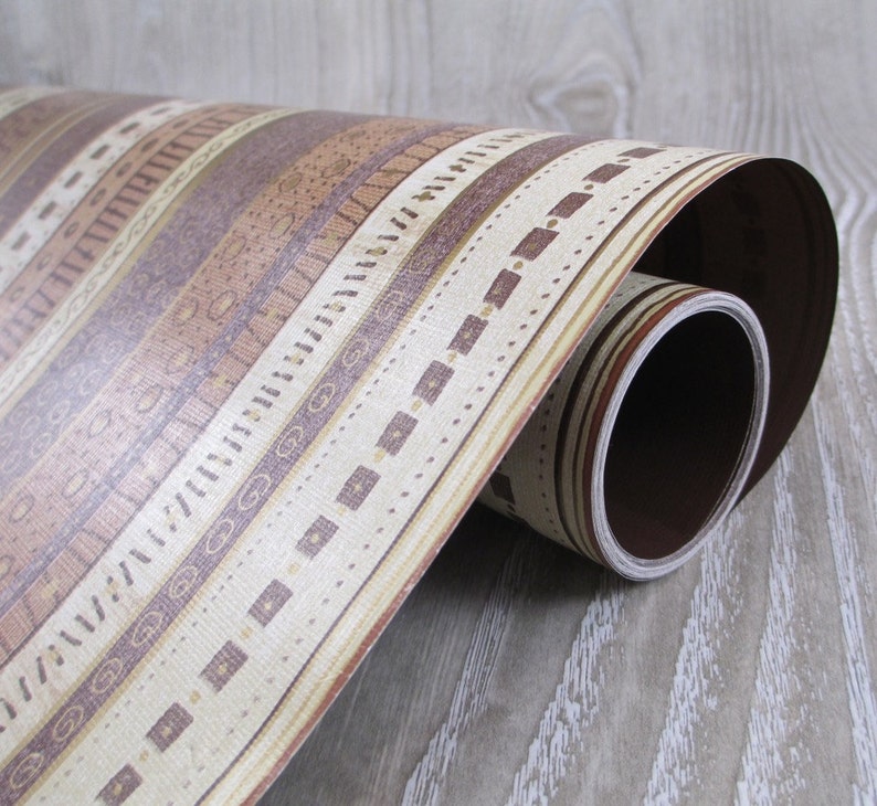 May include: A roll of brown and beige patterned contact paper with a geometric design. The paper is rolled up and the end of the roll is visible.