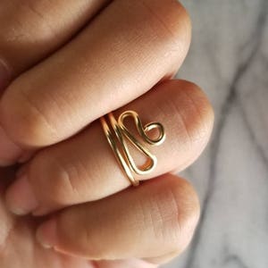 Pu&ograve; includere: Un anello in filo d'oro con un design astratto unico. L'anello &egrave; semplice e delicato, il che lo rende un'ottima scelta per l'uso quotidiano.