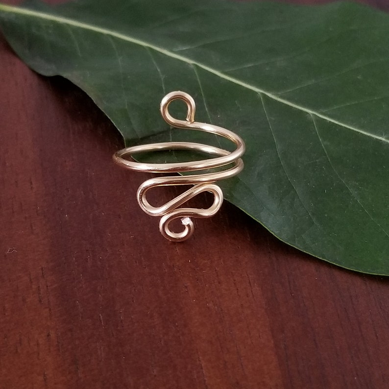 Pu&ograve; includere: Anello in filo d'oro con un design unico e a spirale. L'anello &egrave; realizzato con un unico filo di metallo che viene attorcigliato e modellato a spirale.
