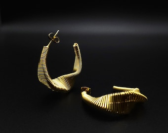 May include: A pair of gold hoop earrings with a unique, wavy, and textured design. The earrings are made of a thin, coiled wire that creates a three-dimensional effect.