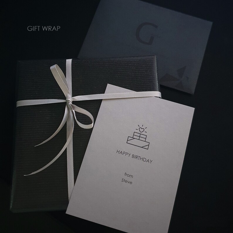 May include: A black gift box with a white ribbon and bow. A white card with a birthday cake icon and the text "Happy Birthday from Steve" is on top of the box.