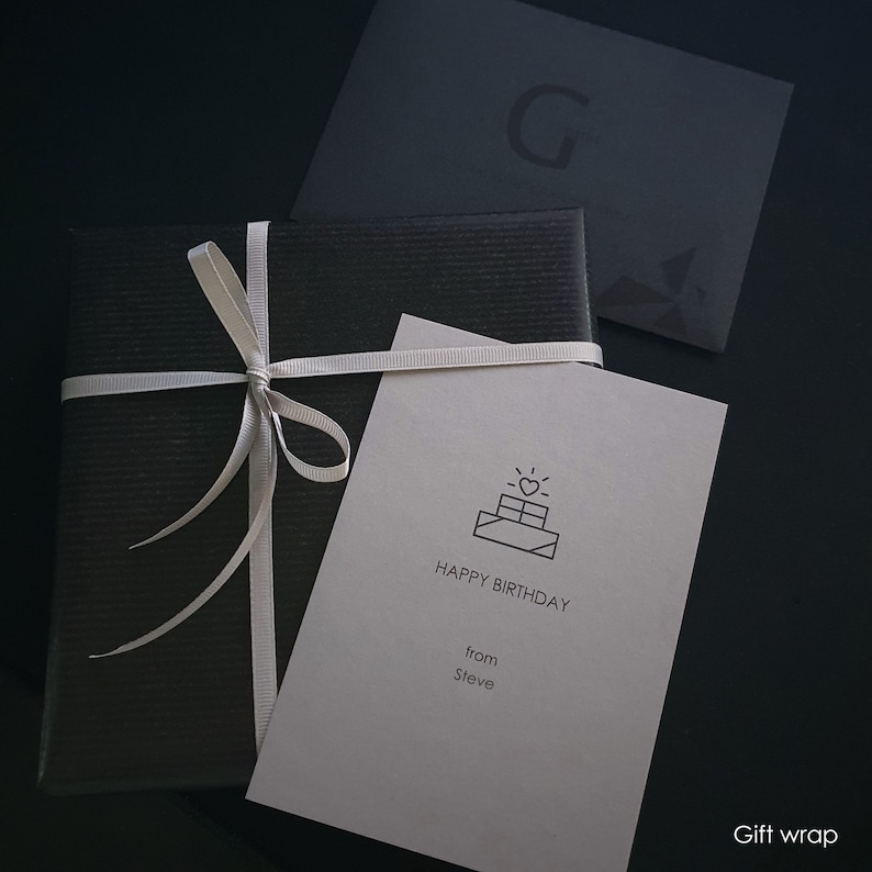 May include: A black gift box with a white ribbon and a white card that says "Happy Birthday from Steve" with a small cake icon.