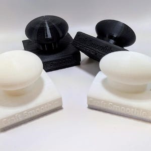 May include: Four stampers, two white and two black, are displayed. Each stamper has a rounded top and a rectangular base. The text "Craft Smoothie" and "Craft Smoothie 2" is visible on the base of the white stampers.
