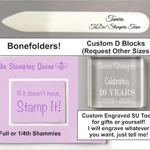 May include: An assortment of crafting tools and accessories. Includes a white bone folder, a clear acrylic stamp block with engraved text, and a light purple card with text that reads "If it doesn't move, Stamp It!"