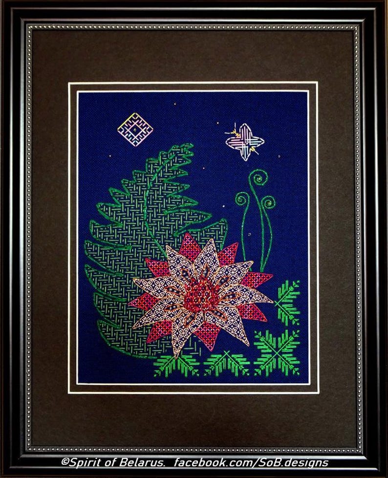 May include: A framed cross-stitch embroidery featuring a stylized flower with pink and red petals, green leaves, and a small butterfly in the upper right corner. The background is a dark blue fabric.