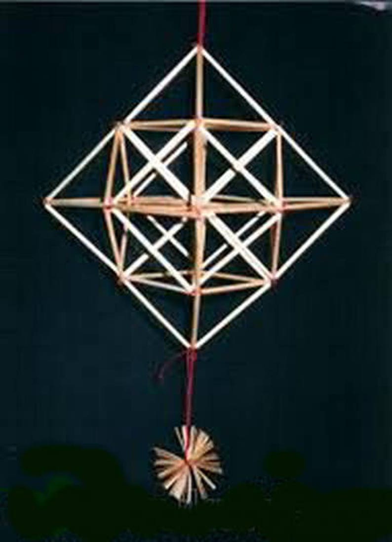 May include: A geometric, three-dimensional structure made of thin, light brown sticks, tied together with red string. The structure is suspended from a red string and has a small, round, brown and white tassel at the bottom.