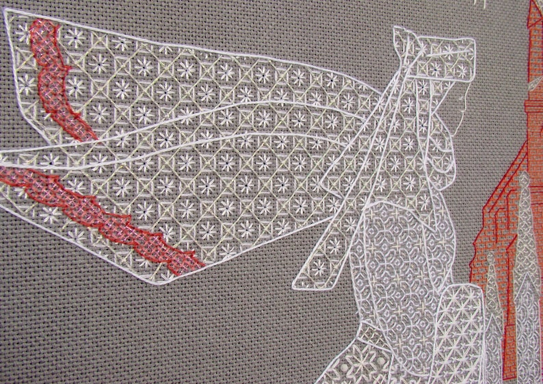 May include: White cross-stitch embroidery on a gray linen fabric. The design features a woman in a white dress and a red ribbon. The woman is standing in front of a building.