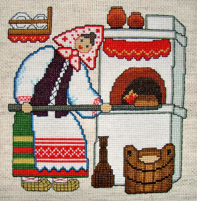 May include: A cross-stitch embroidery depicting a woman in traditional clothing standing in front of a white brick oven. The woman is holding a wooden spoon and there is a basket of bread in front of the oven.