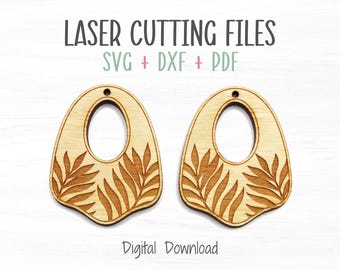 May include: Two wooden laser-cut earring blanks with an oval shape and a central cutout. The earrings feature a leaf design on the lower half. The text "LASER CUTTING FILES" and "SVG + DXF + PDF" are at the top. "Digital Download" is at the bottom.