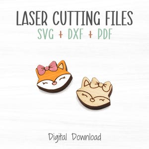 May include: Two laser cut wooden fox head shapes with pink bows. The fox heads are facing forward with closed eyes and a smile. The text "LASER CUTTING FILES SVG + DXF + PDF" is above the fox heads. The text "Digital Download" is below the fox heads.