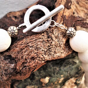 May include: White bead necklace with a silver toggle clasp. The beads are round and have a slightly textured surface.